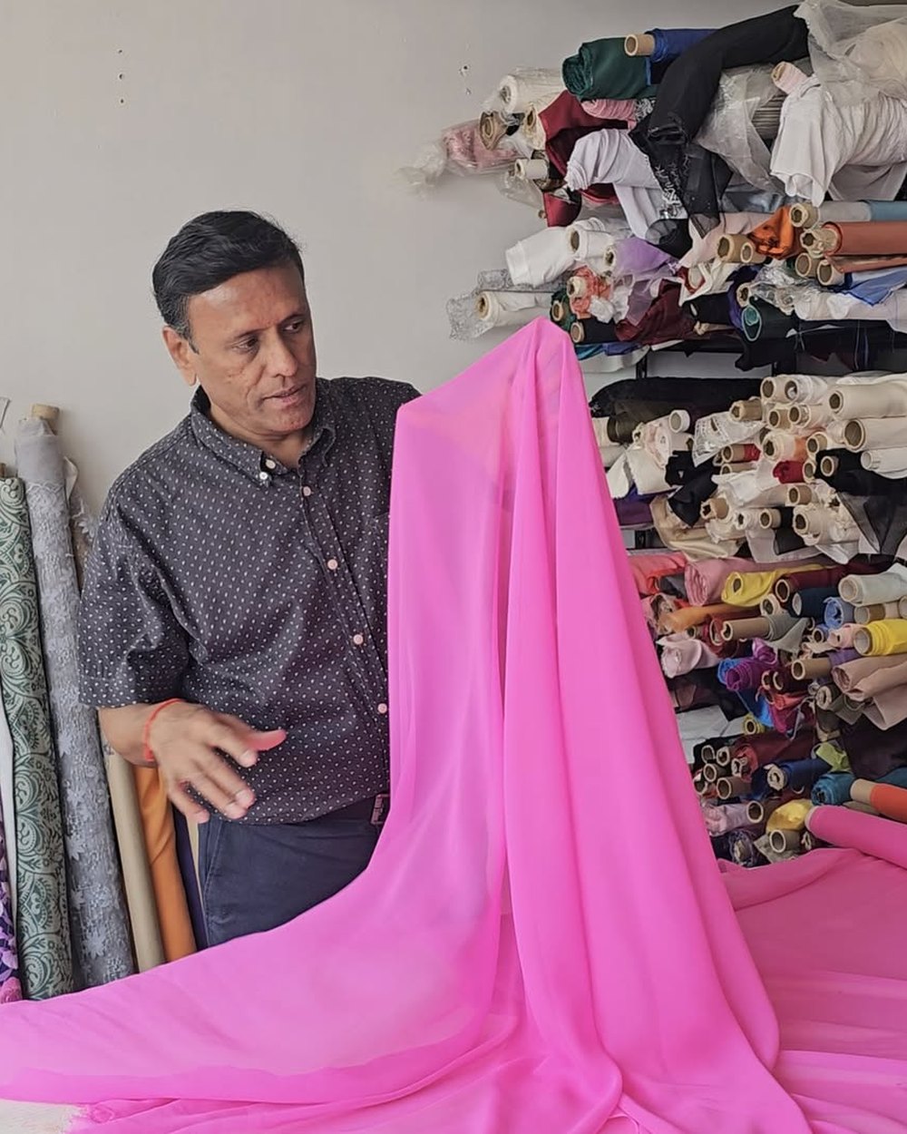 Ragu Subbaraman en el showroom de Sedas Finas Ragus, mostrando una gasa de seda